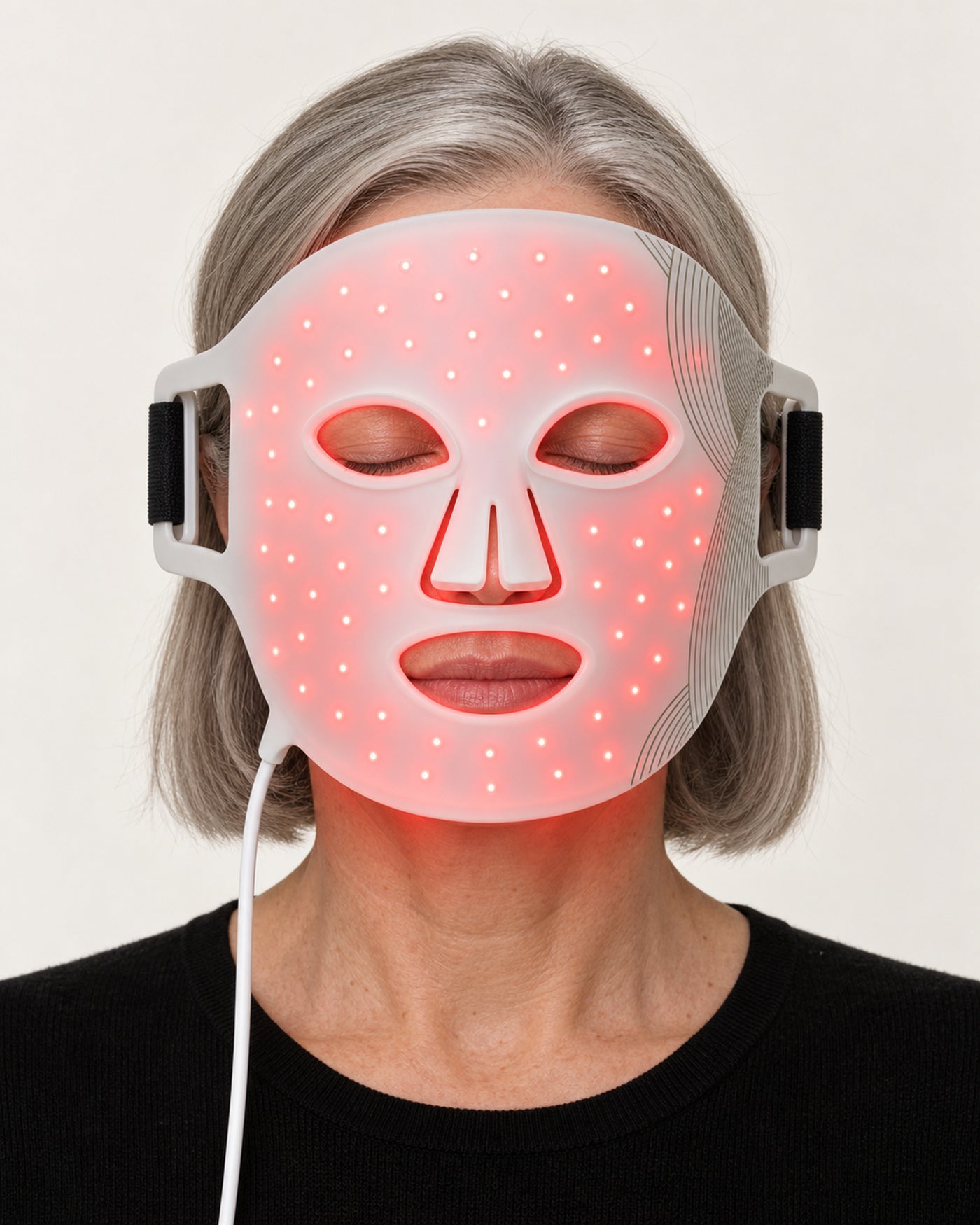 Mature woman wearing the white HYTOVIA LED Face Mask in red light mode